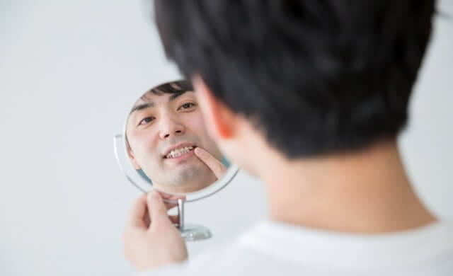 歯並びを鏡でチェックしている男性