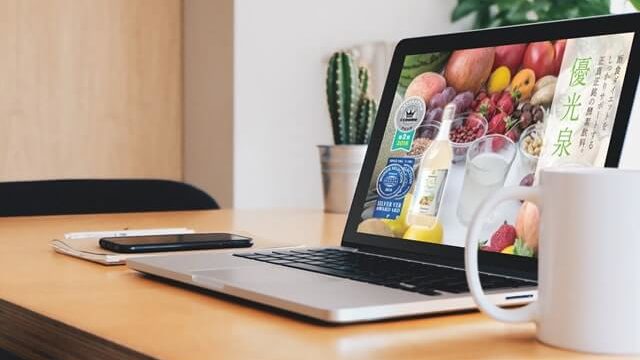 ノートパソコンとコーヒーがテーブルに置いてある