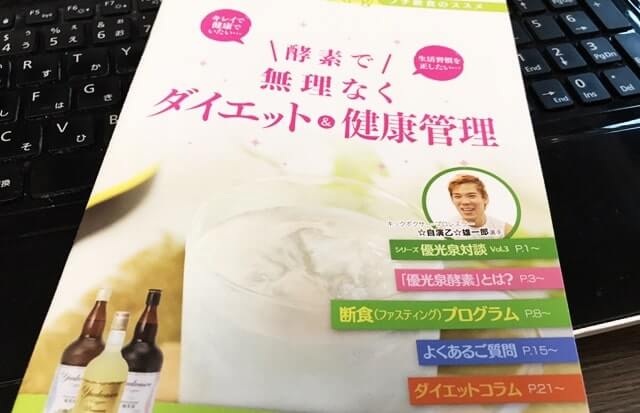 ノートパソコンの上に小冊子が乗っている