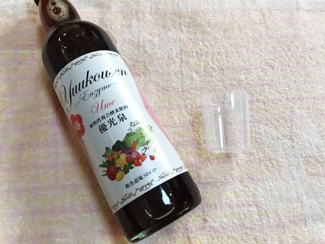 『優光泉』という酵素ドリンクの梅味と計量カップが置かれている